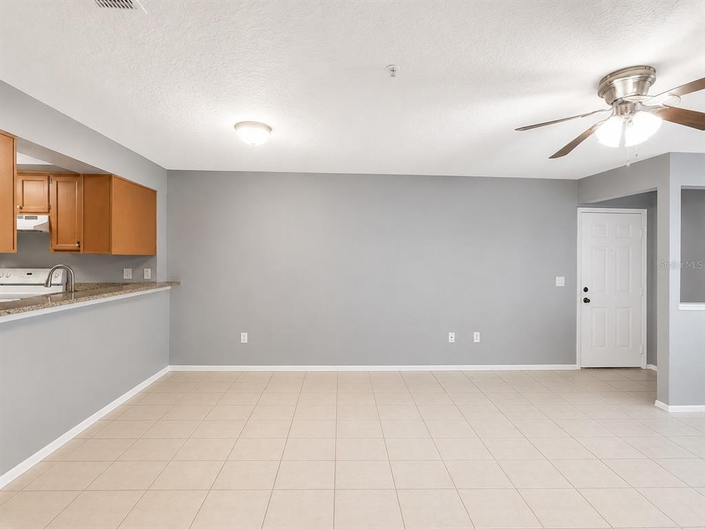 An open-concept dining area features light tile flooring, gray walls, and a ceiling fan — 112 RESERVE CIRCLE UNIT 100, OVIEDO, FL