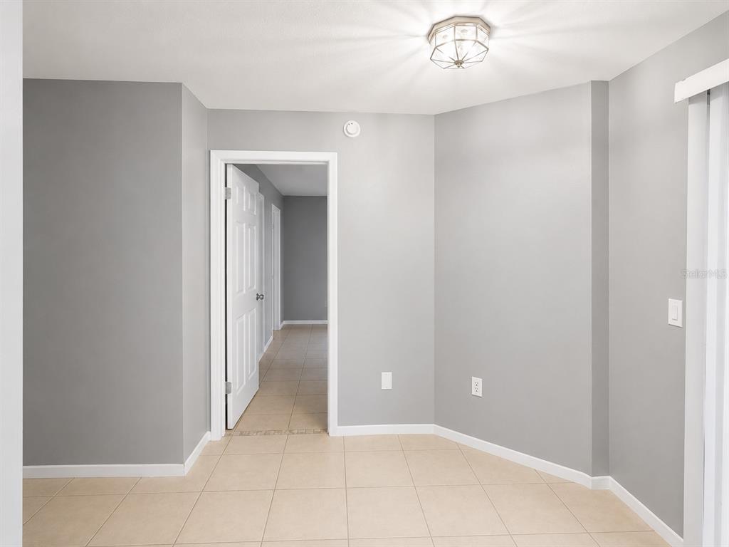 A room with light gray walls, tile flooring, and a doorway leading to a hallway — 112 RESERVE CIRCLE UNIT 100, OVIEDO, FL