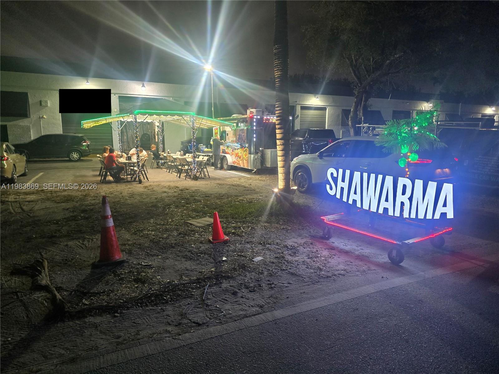 A food truck with outdoor seating and a lighted shawarma sign sits in a parking lot — 6439, Doral FL 33166, DORAL, FL