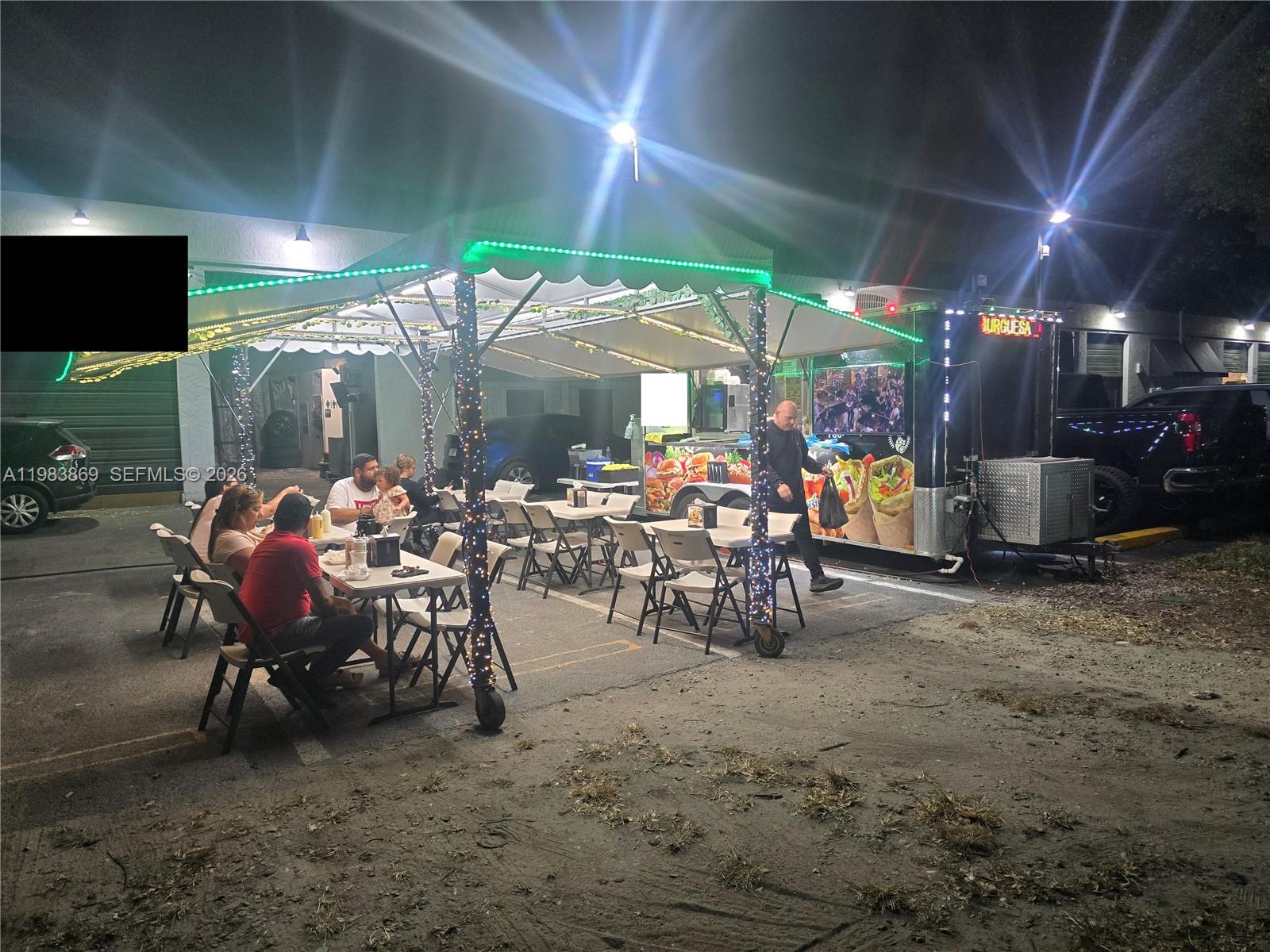 An outdoor food truck setup features a tented dining area with tables and chairs at night — 6439, Doral FL 33166, DORAL, FL