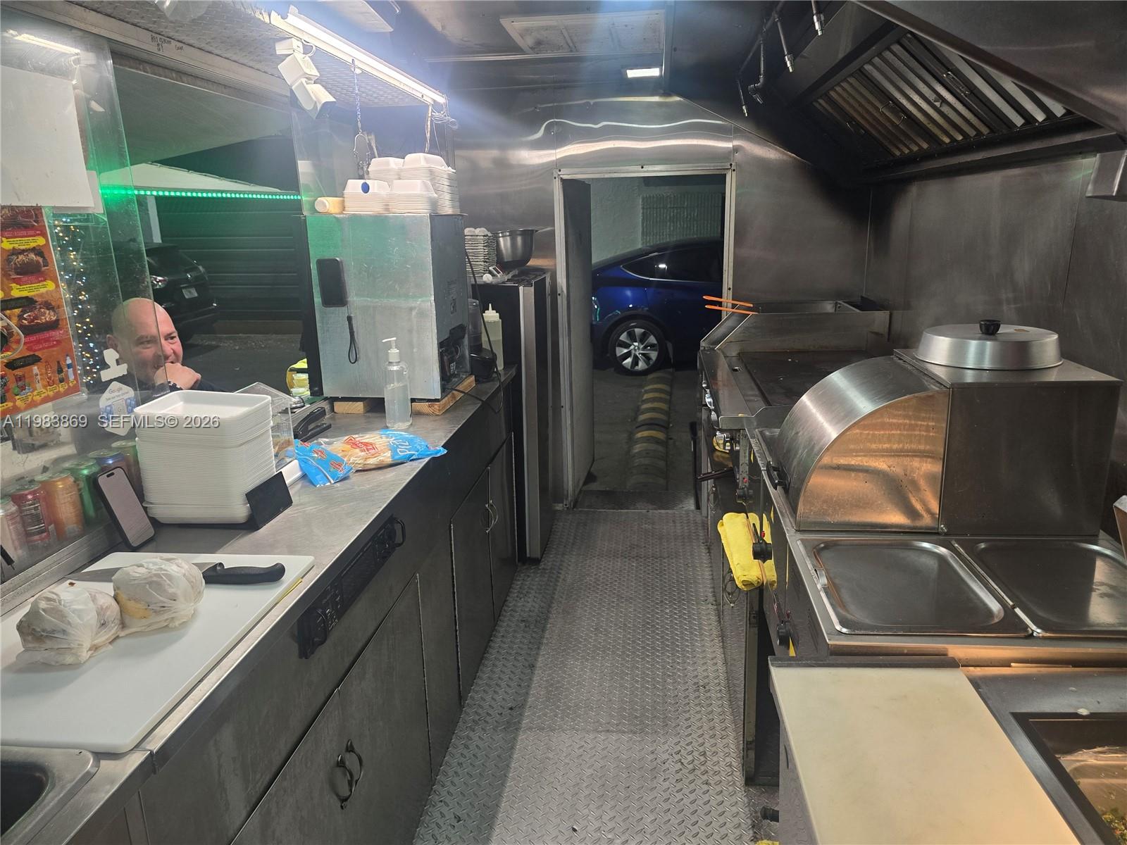 The interior of a food truck features stainless steel counters, cooking equipment, and a service window — 6439, Doral FL 33166, DORAL, FL