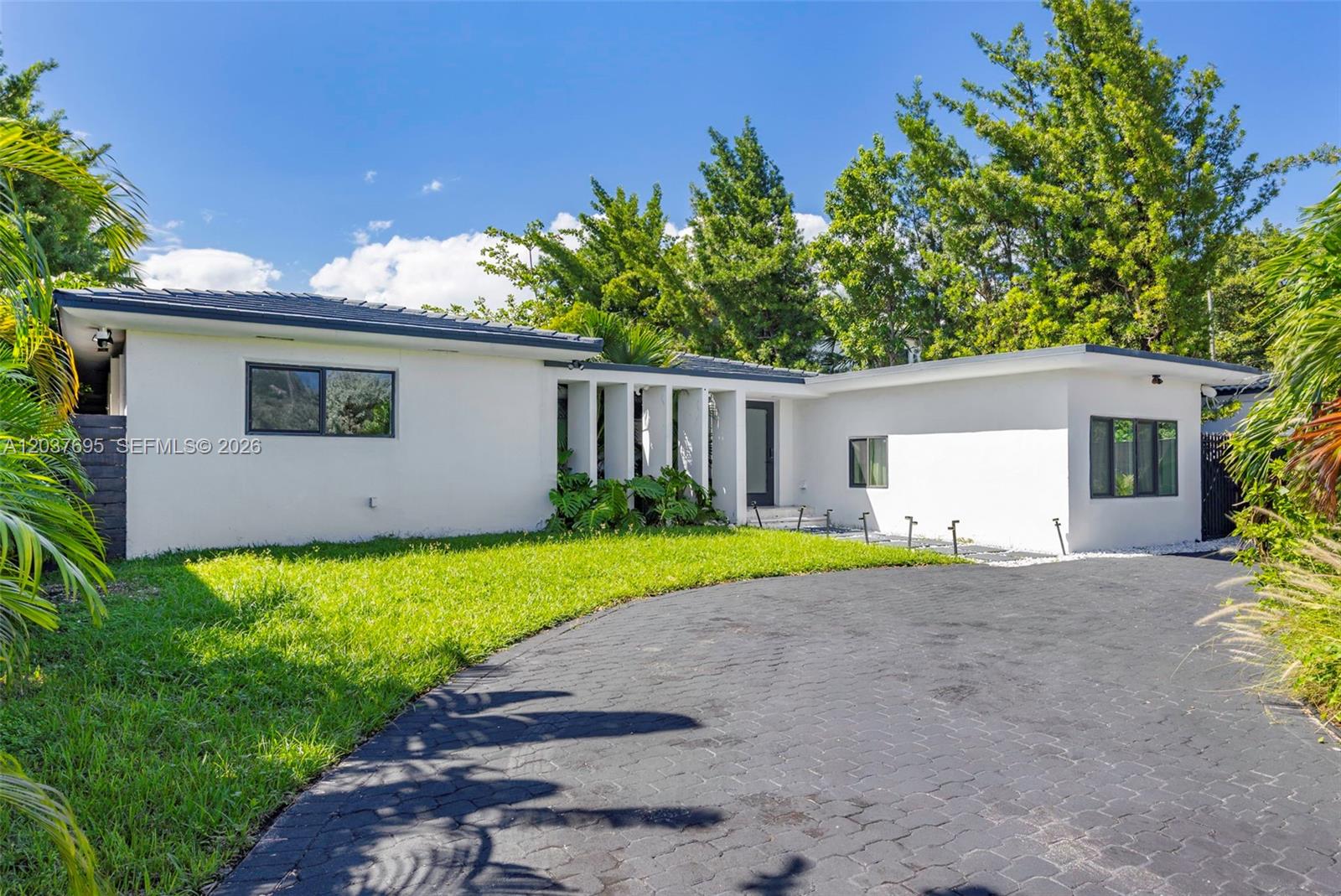 A white, single-story house with a black paved driveway and a decorative columned entryway — 8220 Hawthorne Ave, Miami Beach FL 33141, MIAMI BEACH, FL