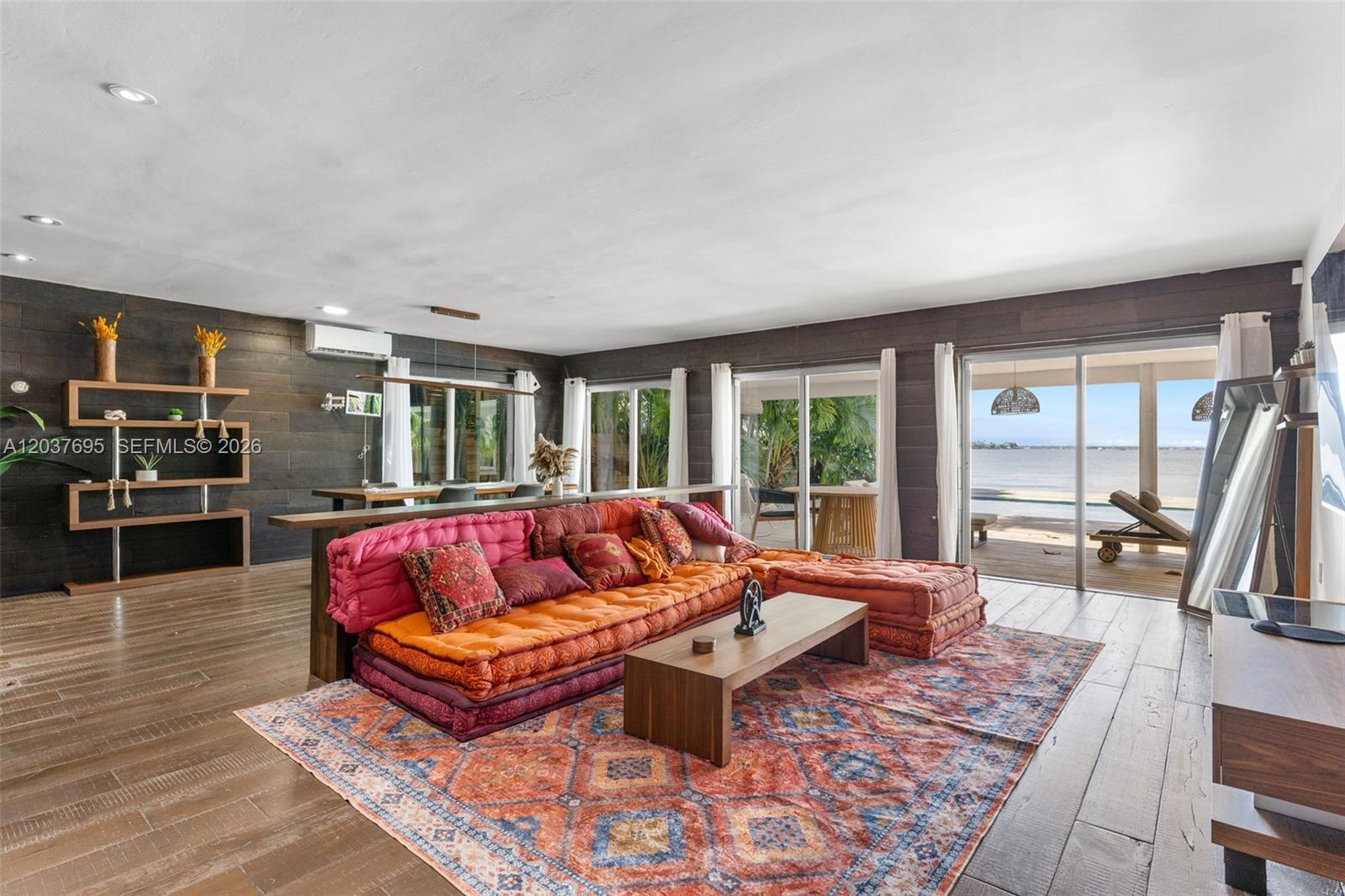 A living room features a colorful floor sofa, a wooden coffee table, and waterfront views — 8220 Hawthorne Ave, Miami Beach FL 33141, MIAMI BEACH, FL