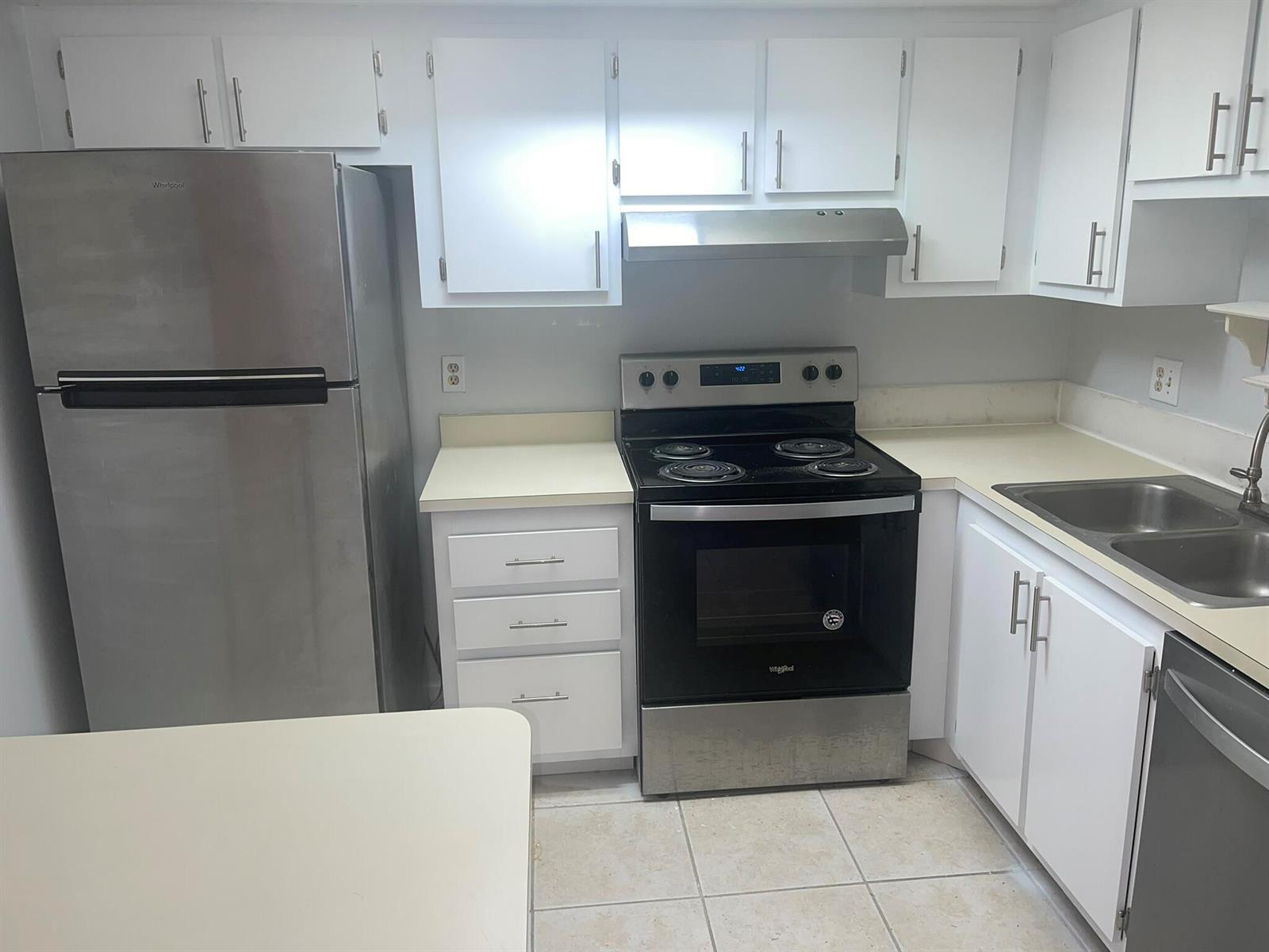 A kitchen features white cabinets, stainless steel appliances, and light-colored countertops — 4185 Oak Terrace Drive, FL 33463, FL