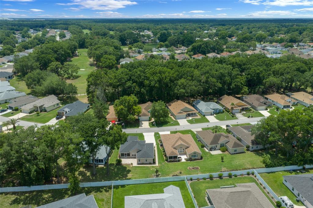 An aerial view shows suburban houses with green lawns and surrounding trees near a golf course — 10972 SW 69TH CIRCLE, OCALA, FL