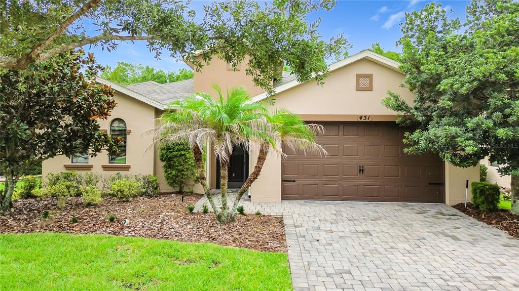 A single-story house with a tan stucco exterior, a paved driveway, and a two-car garage — 451 SCRIPPS RANCH RD, POINCIANA, FL