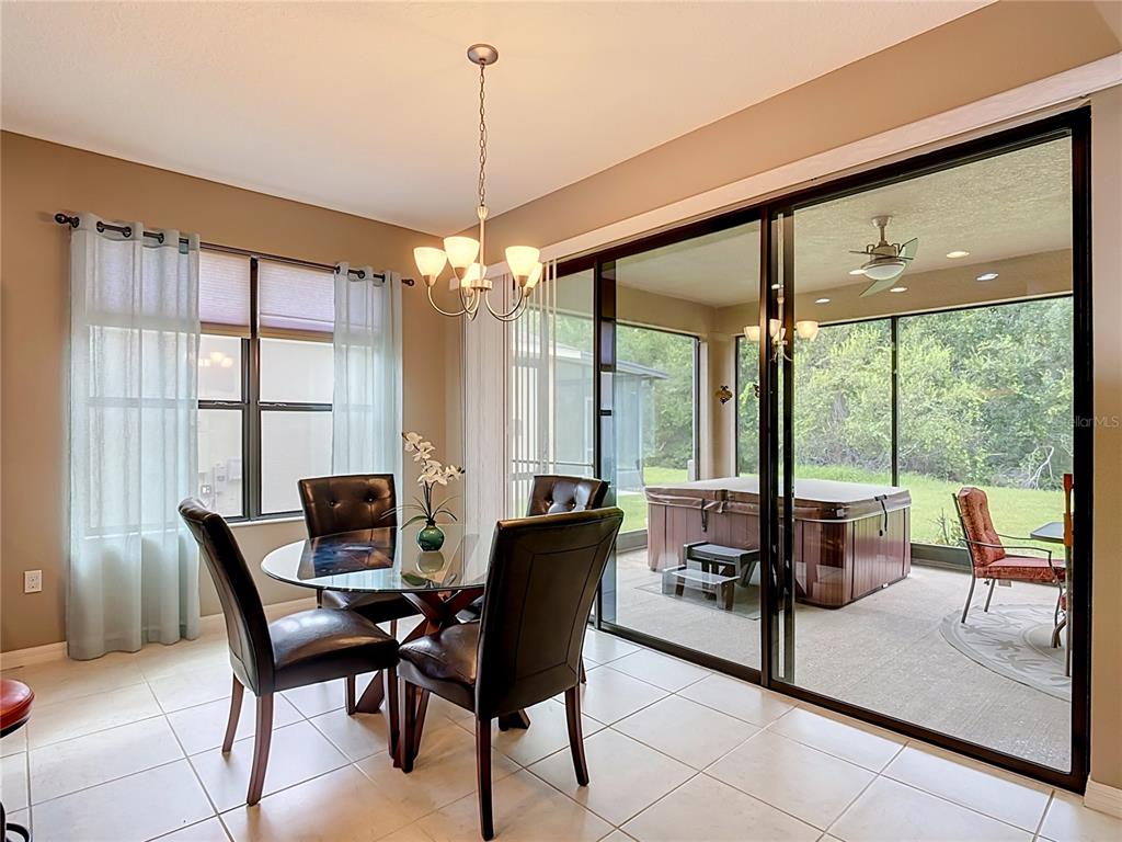 A dining area with a glass table and chairs overlooks a screened patio with a hot tub — 451 SCRIPPS RANCH RD, POINCIANA, FL