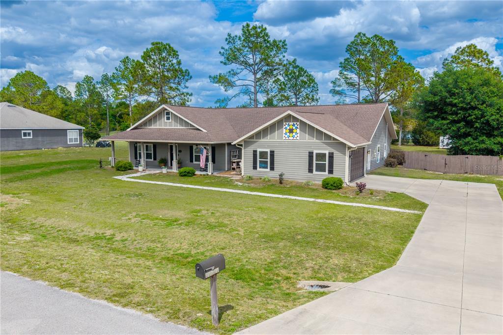 A single-story gray house with a front porch, a concrete driveway, and a large lawn — 11311 NW 74TH COURT, CHIEFLAND, FL