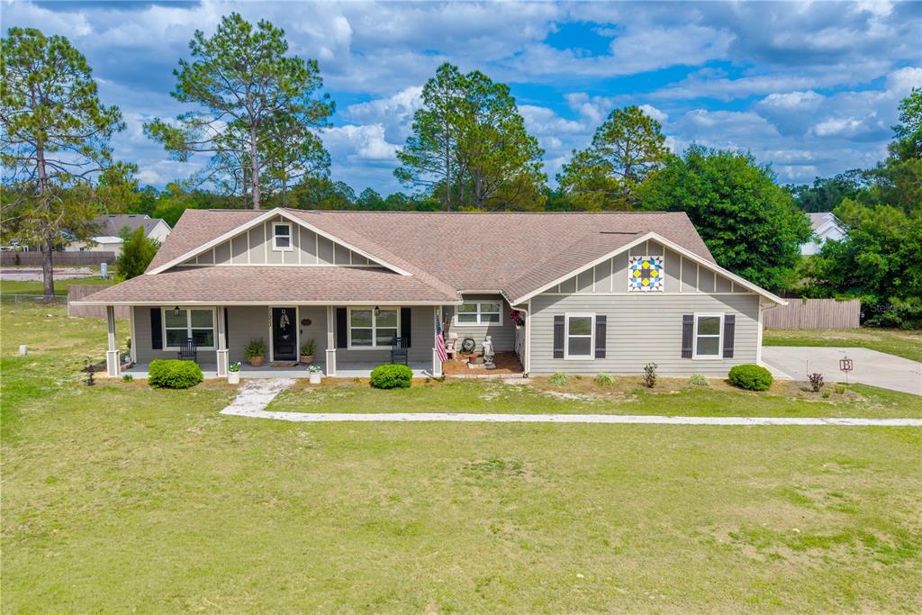 A single-story house with gray siding, a covered front porch, and a quilt-patterned gable accent — 11311 NW 74TH COURT, CHIEFLAND, FL