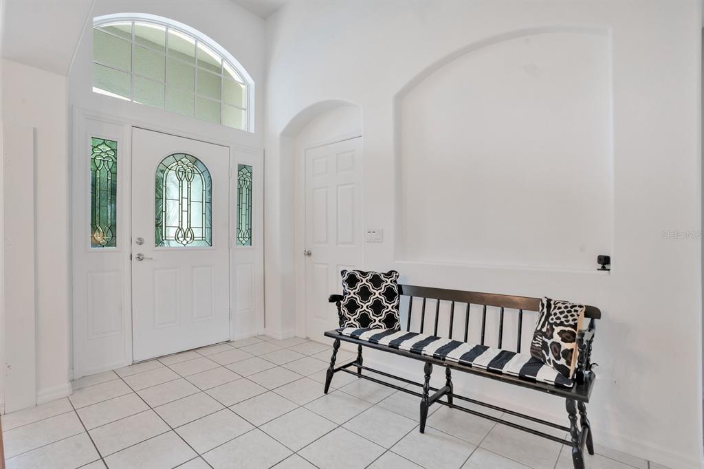 A white kitchen with tile floors overlooks a living area with light wood flooring — 1207 LEGENDARY BOULEVARD, CLERMONT, FL