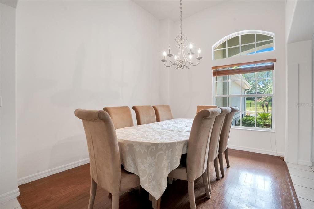 A white kitchen features tile flooring, white cabinetry, white appliances, and a breakfast bar — 1207 LEGENDARY BOULEVARD, CLERMONT, FL