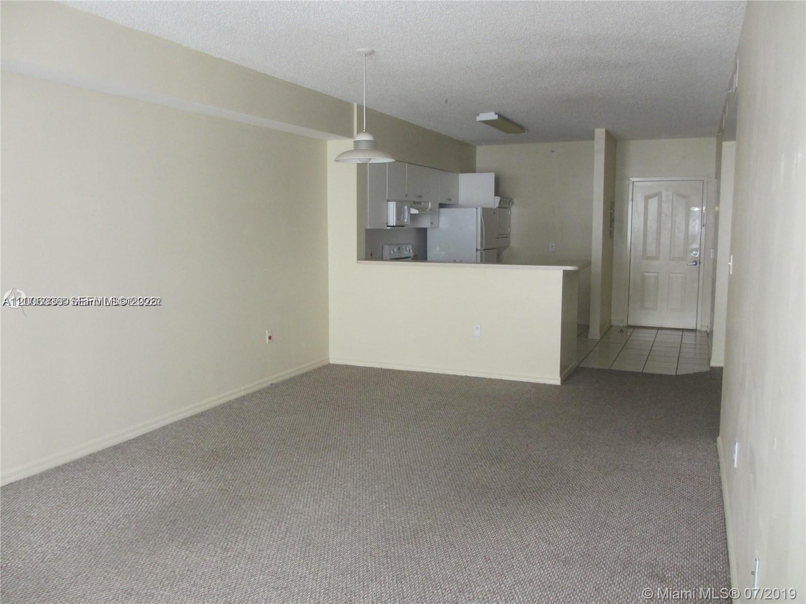 An interior view shows a carpeted living area with a kitchen pass-through and entryway — 5091 NW 7th St # 807, Miami FL 33126, MIAMI, FL