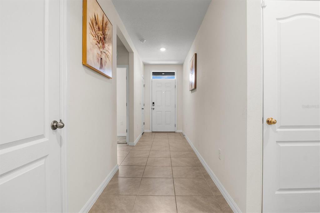 A tiled hallway leads to a white front door with a transom window — 1534 WAX MYRTLE WAY, HAINES CITY, FL
