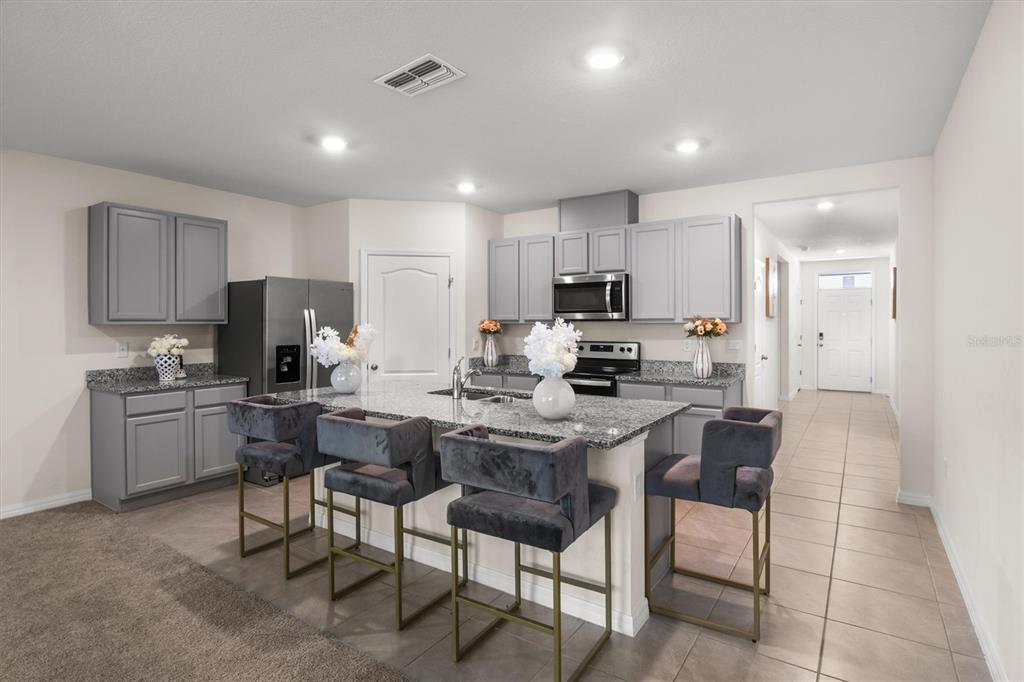 A kitchen with grey cabinets, granite countertops, a central island, and four bar stools — 1534 WAX MYRTLE WAY, HAINES CITY, FL