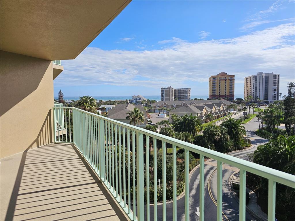 A balcony with a light green railing overlooks a coastal road, palm trees, and buildings — 4 OCEANS WEST BOULEVARD UNIT 601A, DAYTONA BEACH SHORES, FL