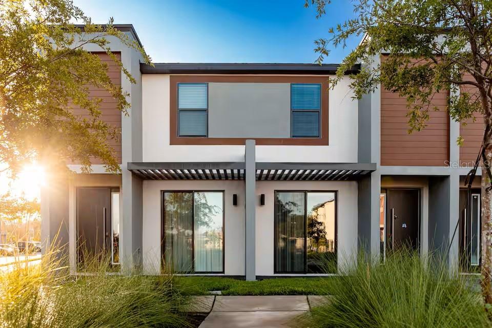 Exterior view of a modern two-story duplex with sliding glass doors and wood-paneled accents — 3261 ENERGY DRIVE, KISSIMMEE, FL