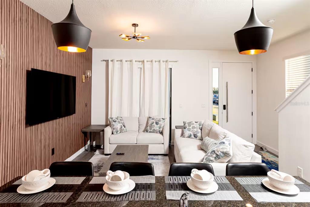 A living room and dining area featuring a wood-slat accent wall and pendant lighting — 3261 ENERGY DRIVE, KISSIMMEE, FL