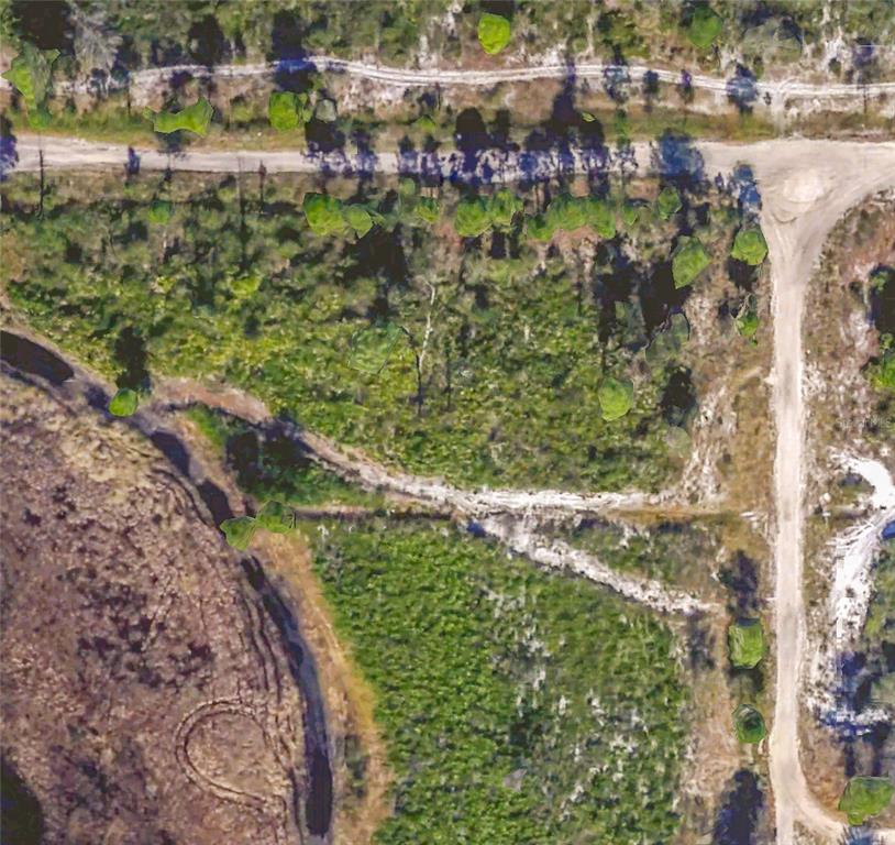 This aerial view shows a dirt road intersecting a rural, partially wooded plot of land — 725 QUAIL AVENUE, SEBRING, FL