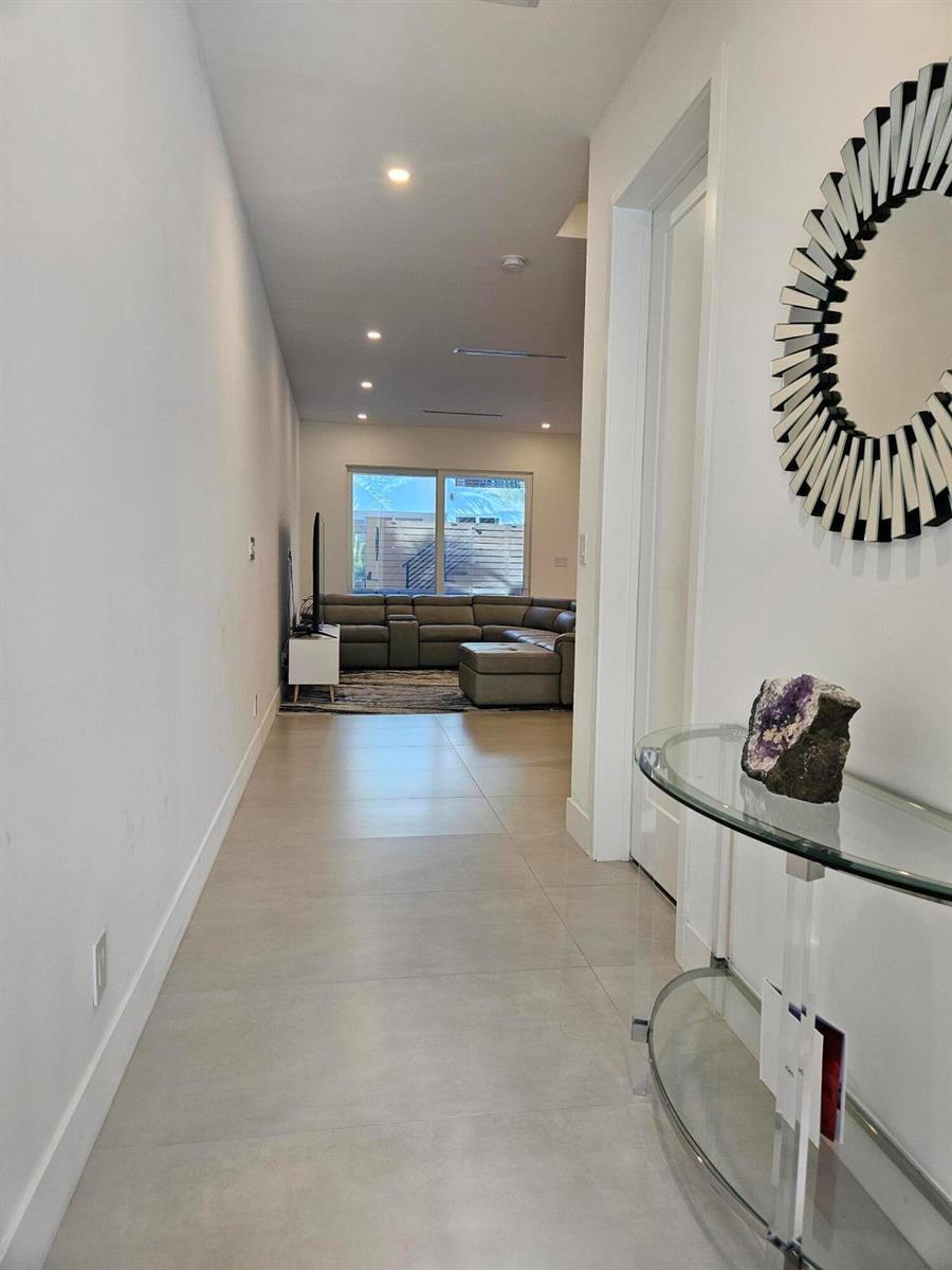 A hallway with light tile flooring leads to a living room featuring a sectional sofa — 2275 SE 7th Street, Pompano Beach FL 33062, POMPANO BEACH, FL