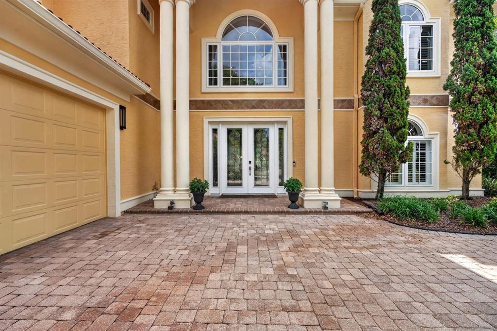 A paved driveway leads to the double front doors of a yellow house with columns — 18 HAMMOCK BEACH PARKWAY, PALM COAST, FL