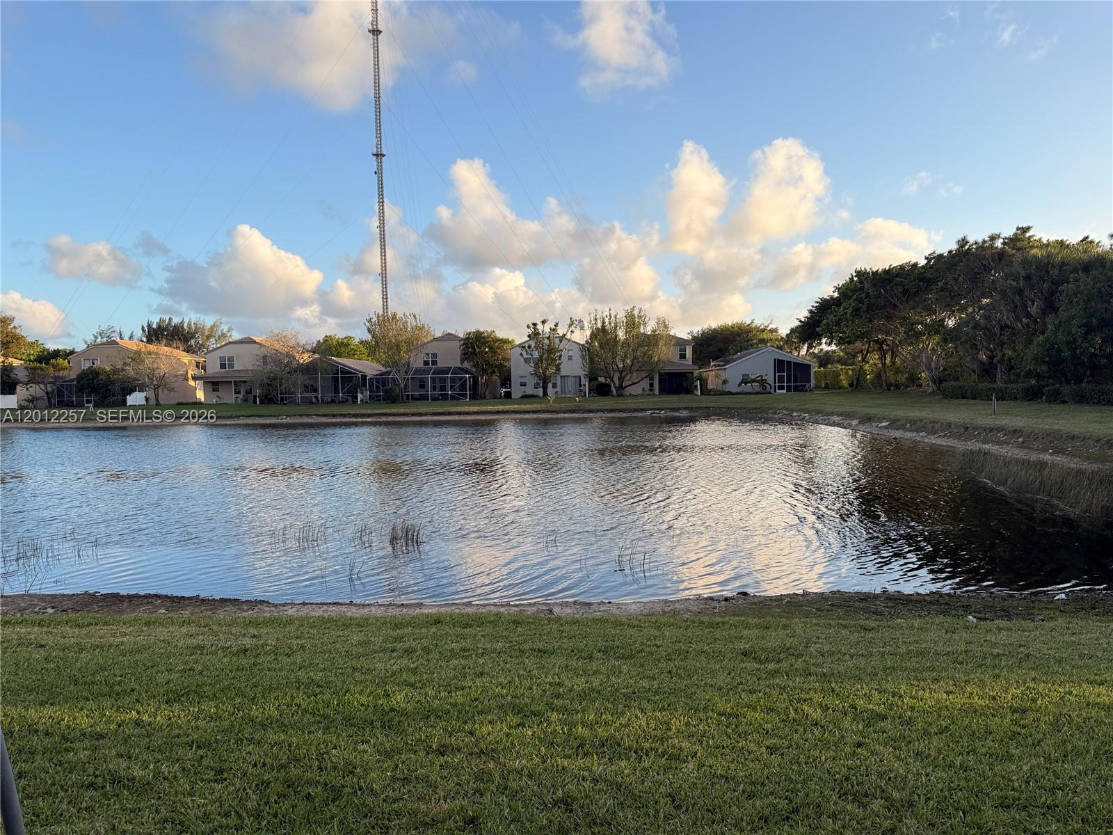 A pond sits in front of several suburban houses under a blue sky — 10434 White Pinto Ct, Lake Worth FL 33449, LAKE WORTH, FL