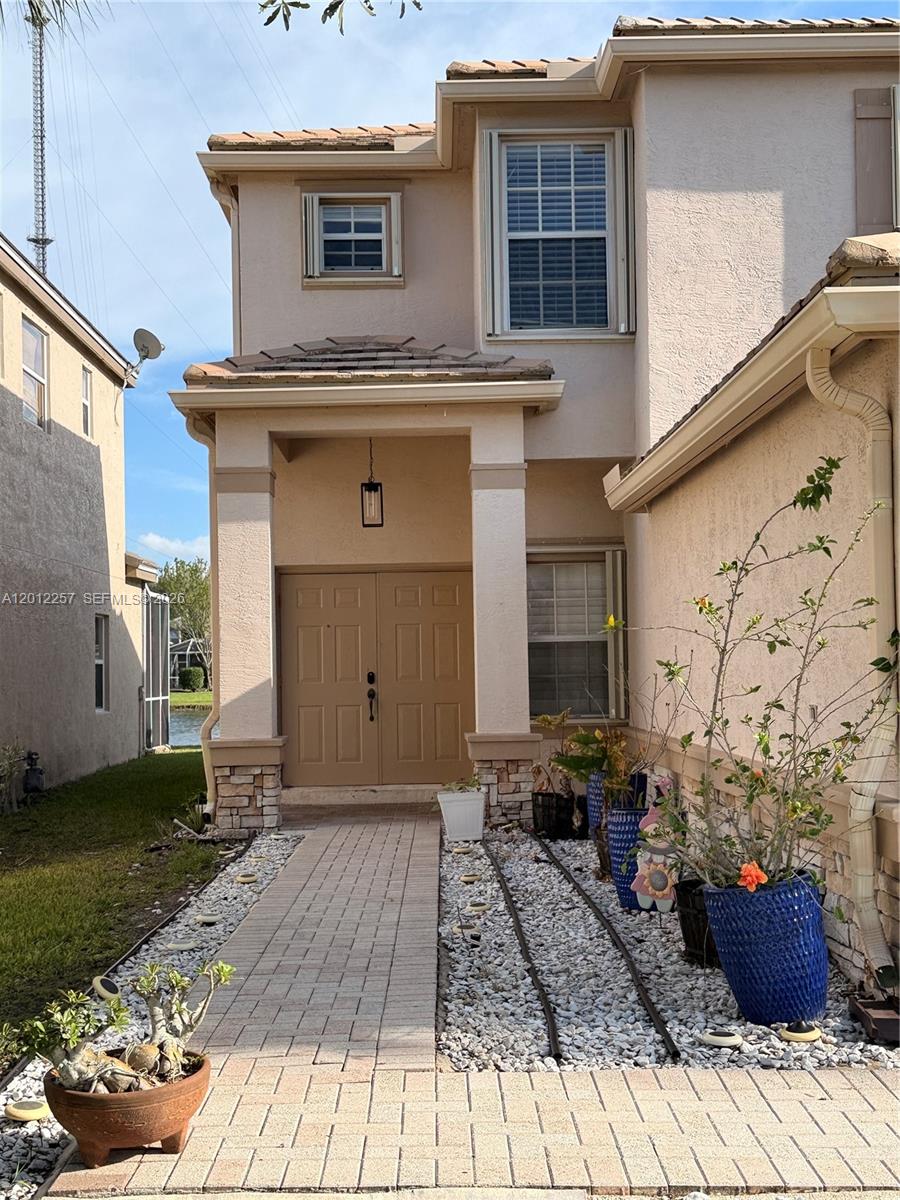 A beige two-story house features a double front door, stone accents, and a paved walkway — 10434 White Pinto Ct, Lake Worth FL 33449, LAKE WORTH, FL