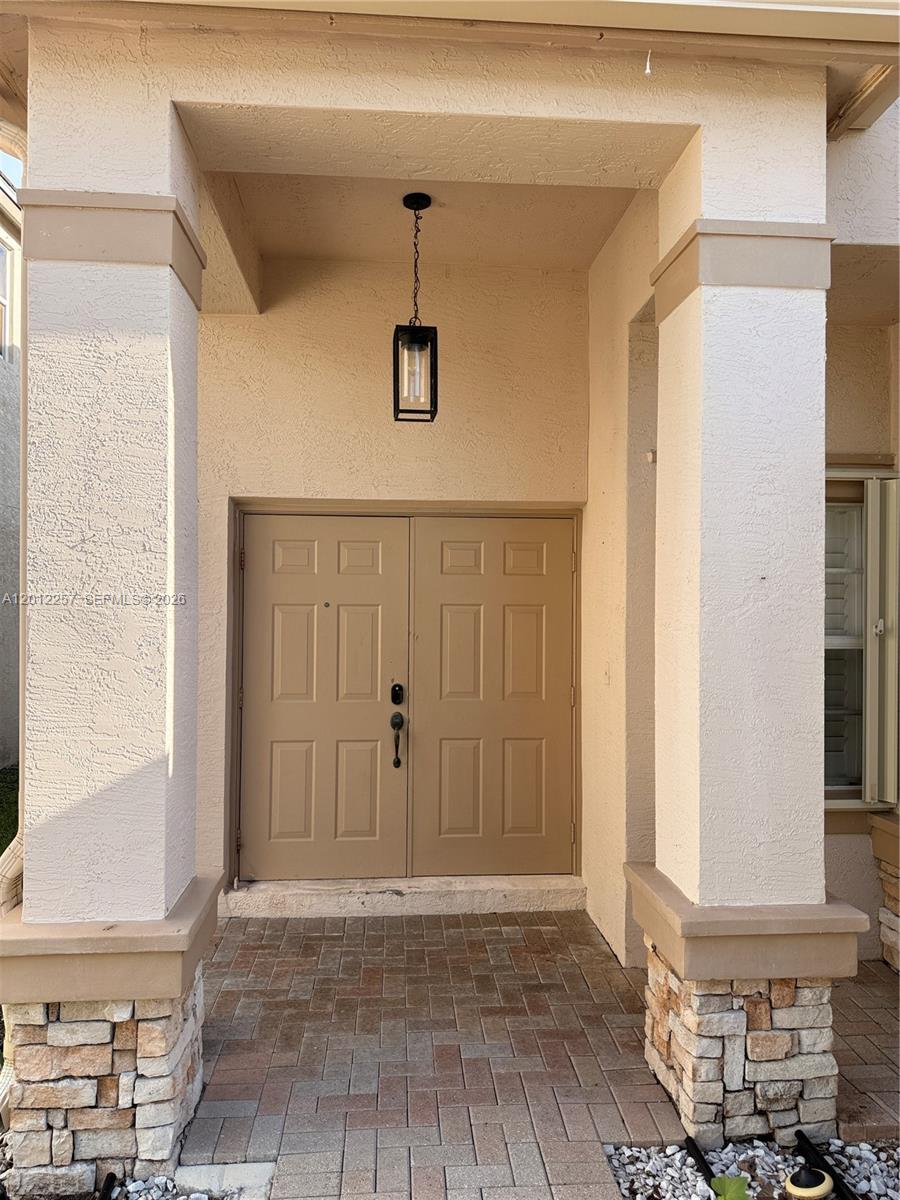 A covered entryway features a double door, stone-based columns, and a hanging lantern light fixture — 10434 White Pinto Ct, Lake Worth FL 33449, LAKE WORTH, FL