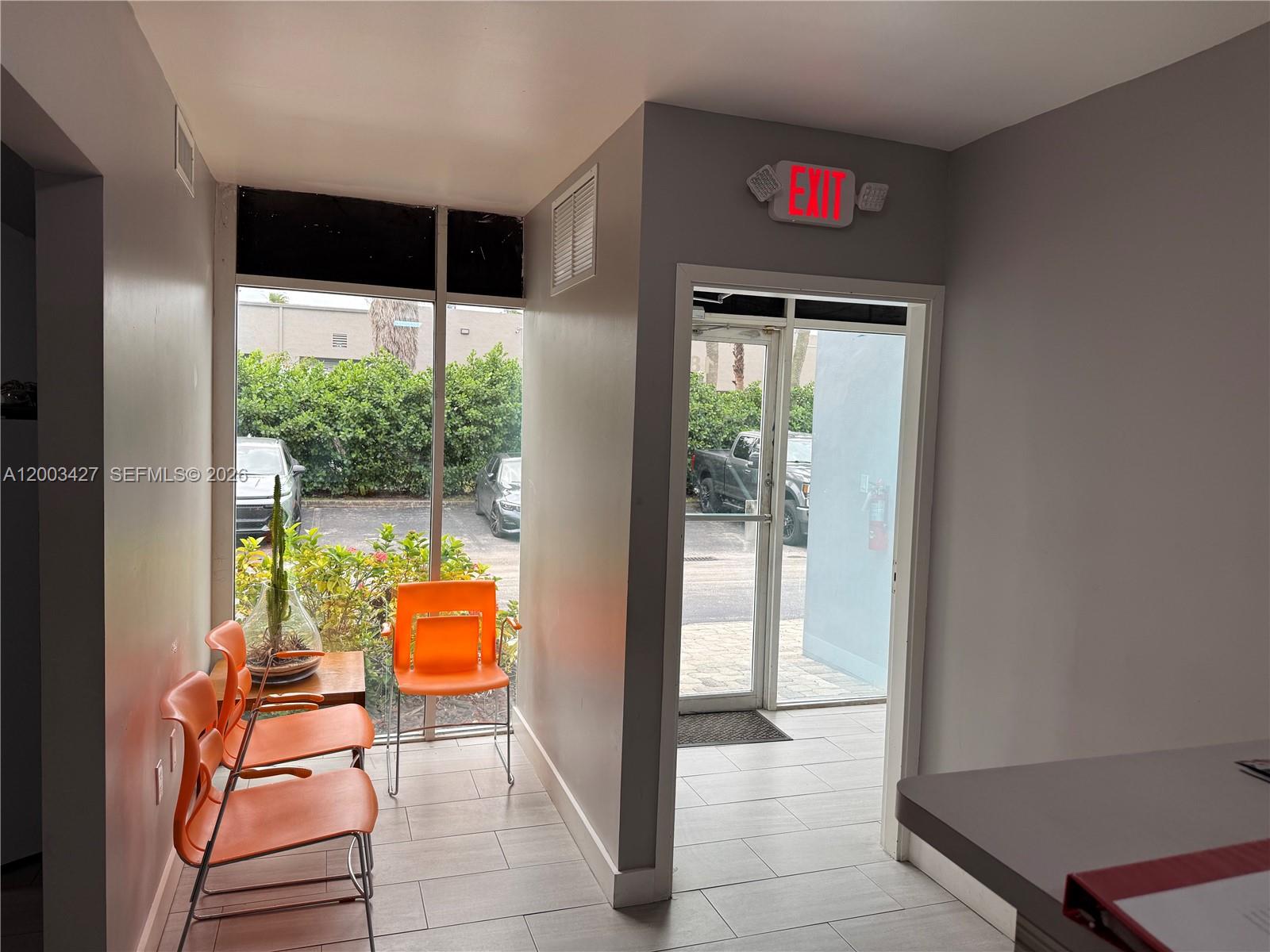 A waiting area features orange chairs, a glass door, and a red exit sign — 16155 SW 117th Ave # B18, Miami FL 33177, MIAMI, FL