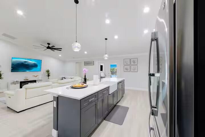 A modern open-concept kitchen with a dark gray island and white countertops facing a living area — 11038 Persimmon Boulevard, West Palm Beach FL 33411, WEST PALM BEACH, FL