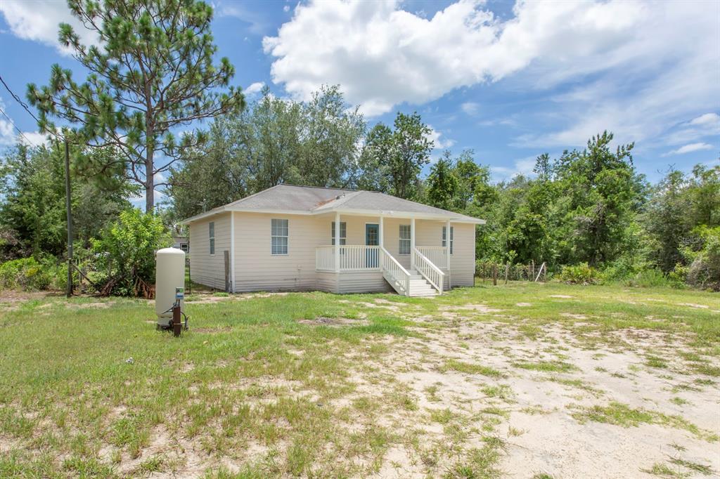 A single-story house with light siding and a front porch sits on a grassy lot — 11960 NE 67TH LANE, WILLISTON, FL