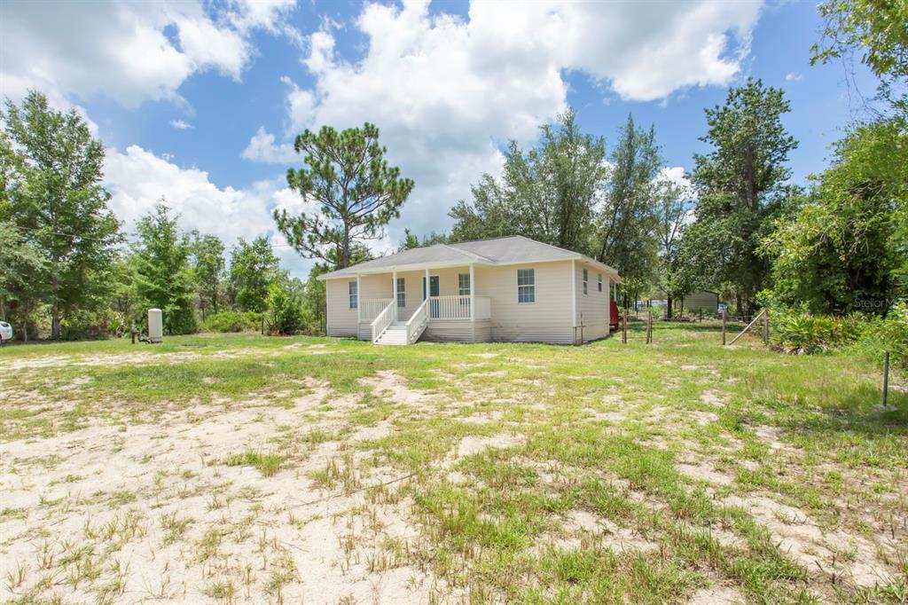 A light-colored, single-story house with a front porch sits on a large, grassy lot — 11960 NE 67TH LANE, WILLISTON, FL