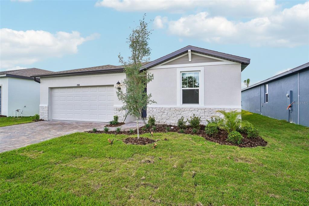 A single-story house with a white garage, stone veneer accents, and a front lawn — 13696 UMBER FOREST STREET, HUDSON, FL