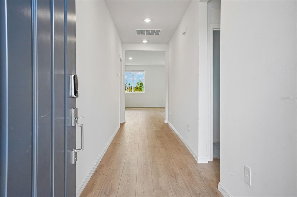 A view from an entryway looking down a hallway with light wood-look flooring — 13696 UMBER FOREST STREET, HUDSON, FL