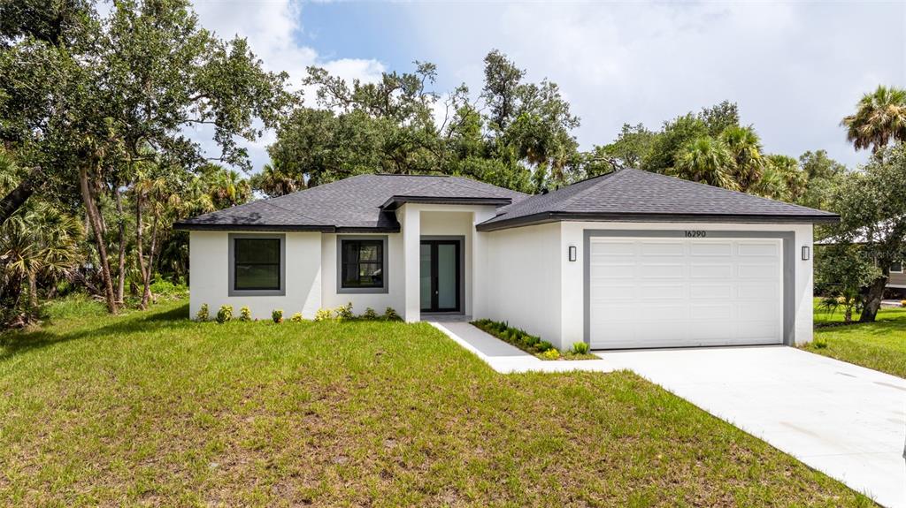 A single-story white house with a dark roof, two-car garage, and a front entryway — 16290 BANYAN AVENUE, PORT CHARLOTTE, FL