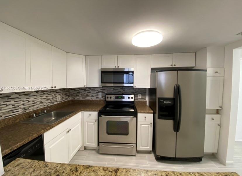 A kitchen features white cabinets, stainless steel appliances, a brown countertop, and a tiled backsplash — 13499 Biscayne Blvd # 1507, North Miami FL 33181, NORTH MIAMI, FL