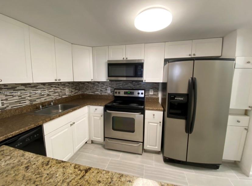 A kitchen features white cabinets, stainless steel appliances, a granite countertop, and a tiled backsplash — 13499 Biscayne Blvd # 1507, North Miami FL 33181, NORTH MIAMI, FL