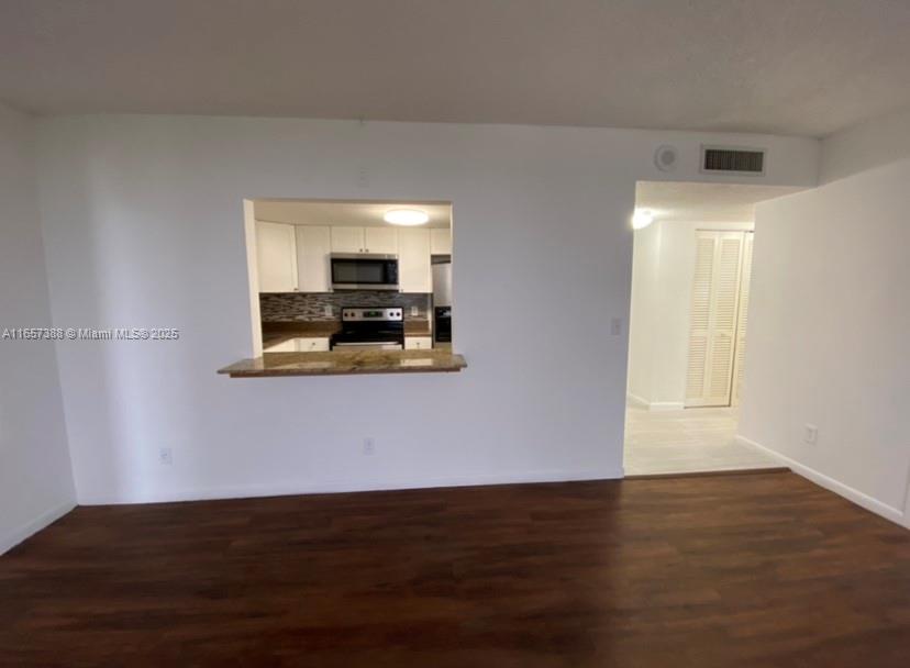 A living area features dark wood-look flooring and a pass-through opening to the kitchen — 13499 Biscayne Blvd # 1507, North Miami FL 33181, NORTH MIAMI, FL