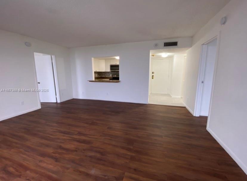 An interior view of a living area with wood-look flooring and a kitchen pass-through window — 13499 Biscayne Blvd # 1507, North Miami FL 33181, NORTH MIAMI, FL