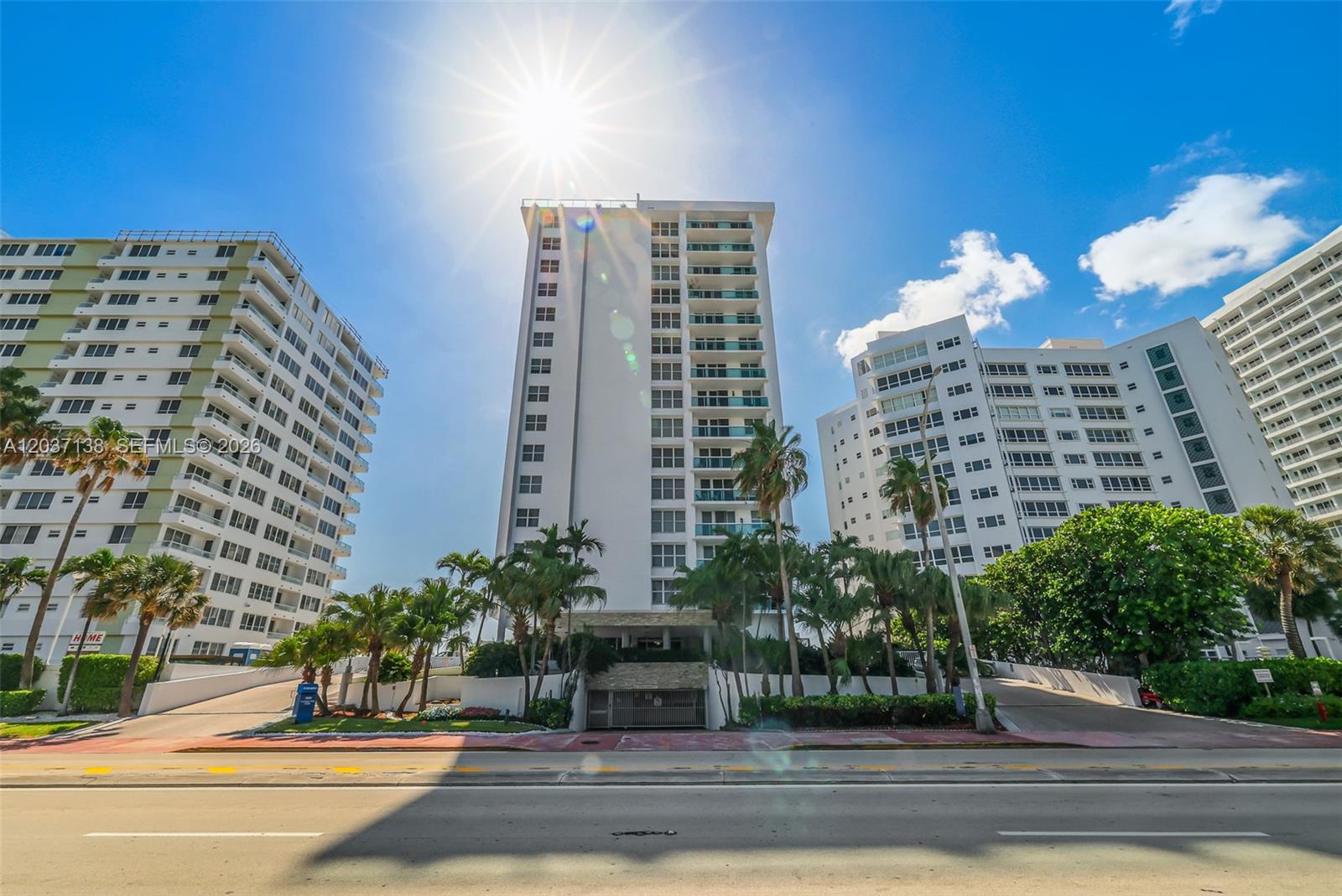 Three white high-rise apartment buildings stand behind palm trees under a bright sun — 5001 Collins Ave # 6E, Miami Beach FL 33140, MIAMI BEACH, FL
