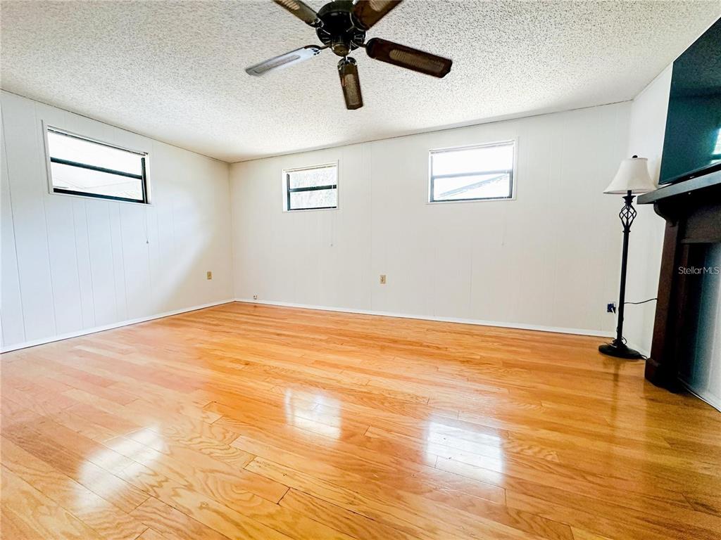 An empty room features light wood flooring, white paneled walls, and a ceiling fan — 1690 S MCADOO AVENUE, BARTOW, FL