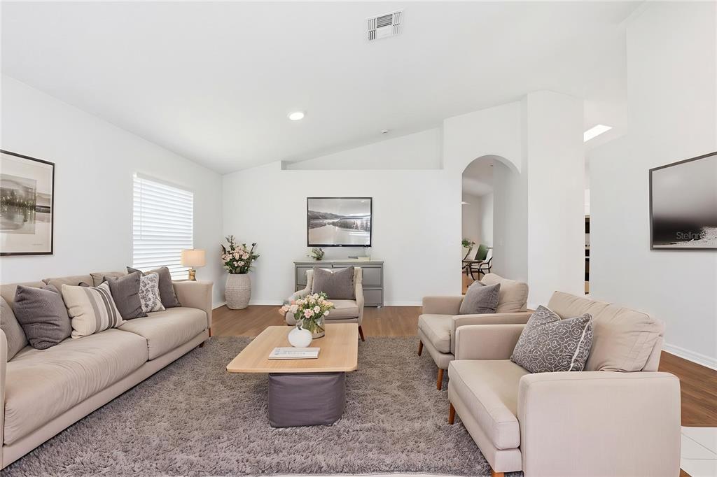 A living room features a beige sofa, two armchairs, and a coffee table on a rug — 1353 CRIMSON CLOVER LANE, WESLEY CHAPEL, FL