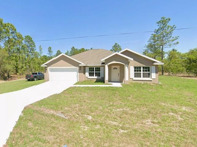 A tan single-story house with a white garage door sits on a grassy lot — SW HARBOR HILLS RD, DUNNELLON, FL