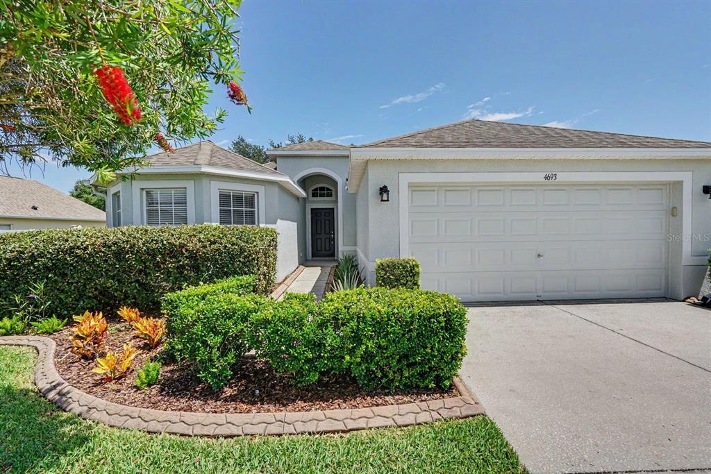 A single-story house with a gray exterior, a two-car garage, and a landscaped front yard — 4693 HARTS BROOK LANE, MULBERRY, FL
