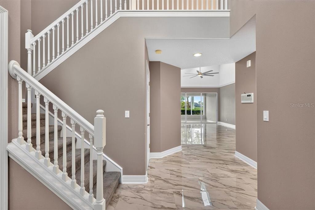 A foyer with marble-look tile flooring leads to a staircase and an open living area — 1975 RUTGERS PLACE, PORT ORANGE, FL