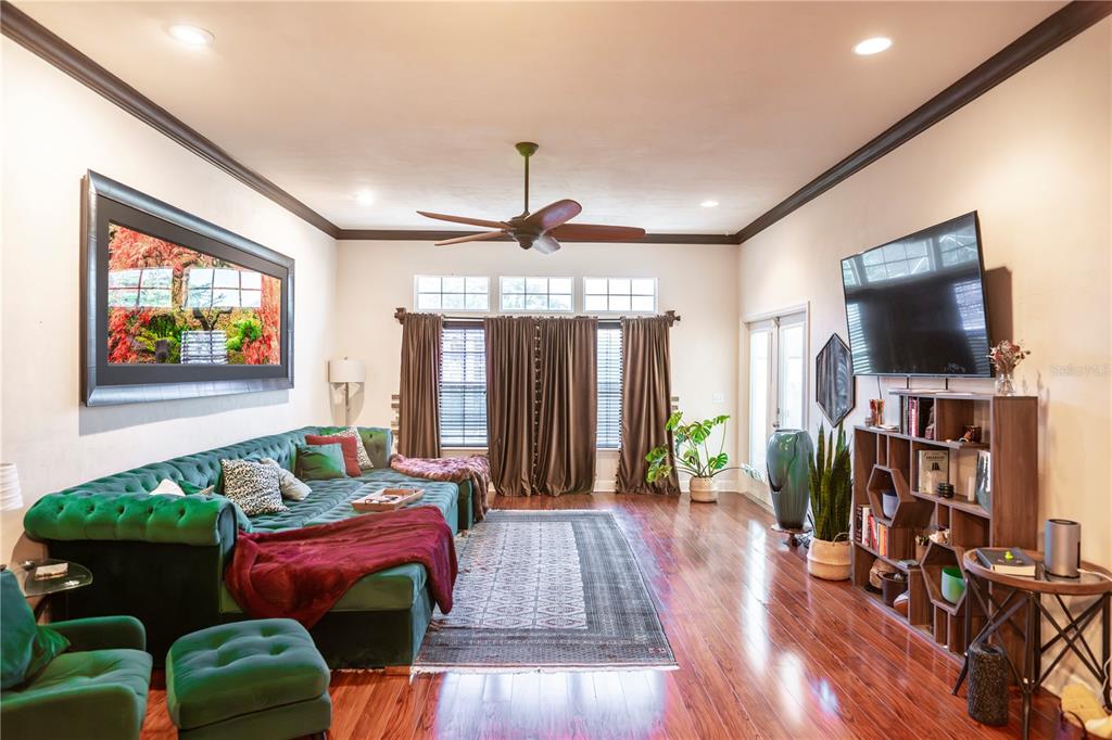 A living room features a green velvet sectional, hardwood floors, and a wall-mounted television — 11774 NW 60TH DRIVE, ALACHUA, FL
