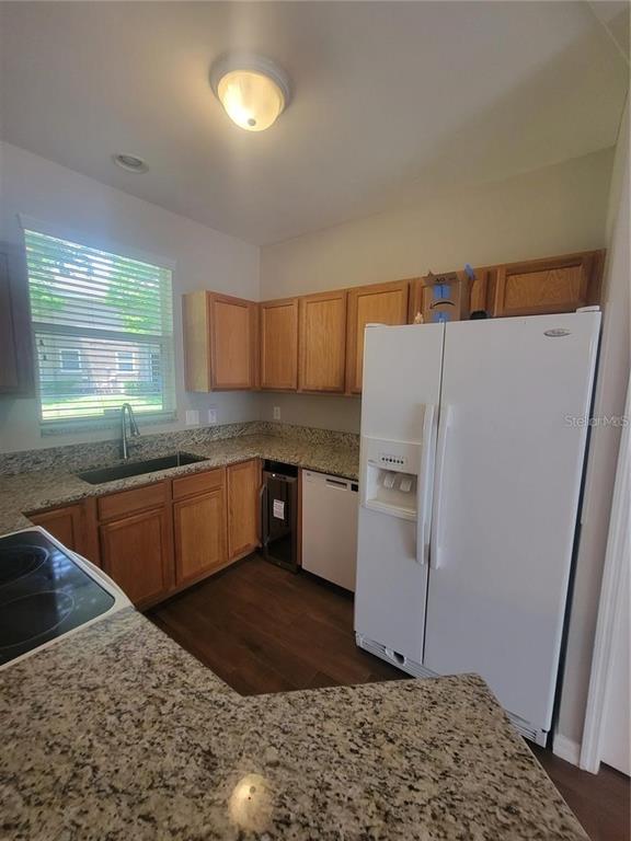 A kitchen features oak cabinets, granite countertops, a white refrigerator, and a window above the sink — 2221 GOLDEN OAK LANE, VALRICO, FL