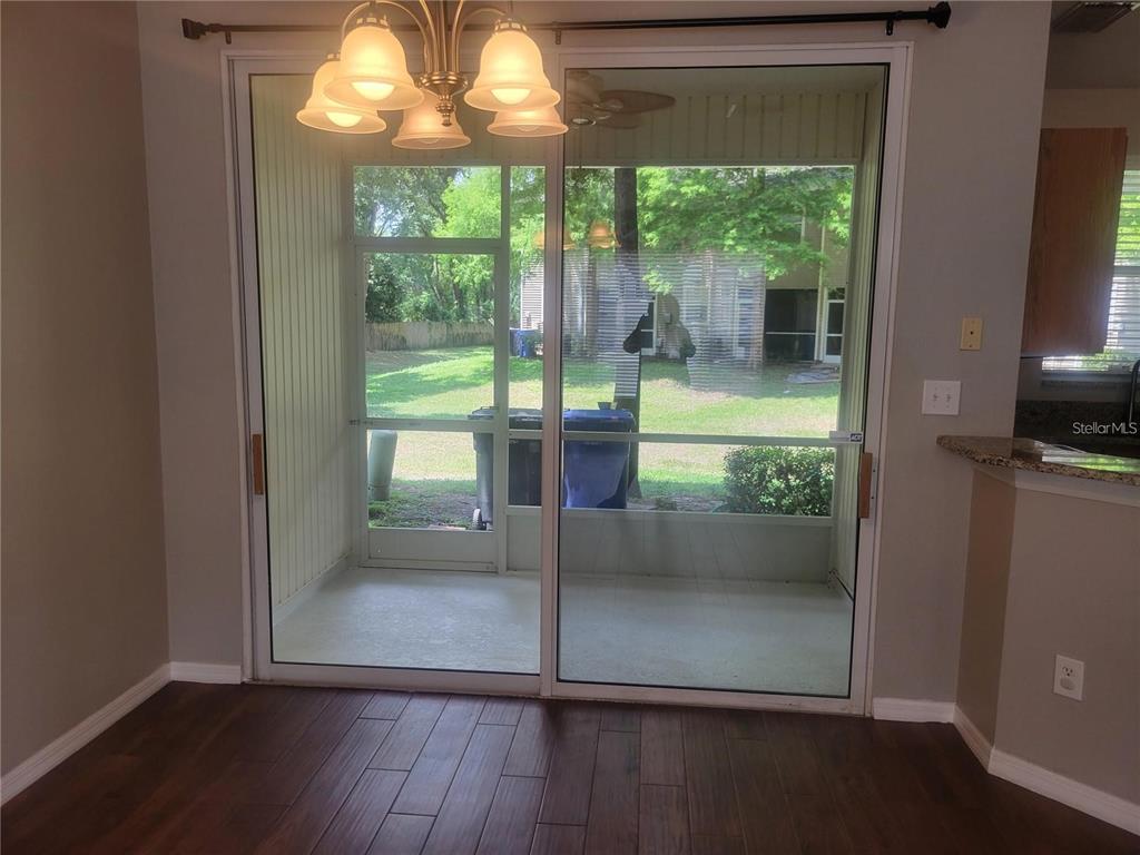 A dining area with wood-look tile flooring features a sliding glass door leading to a patio — 2221 GOLDEN OAK LANE, VALRICO, FL