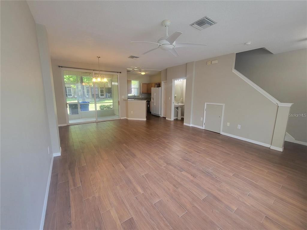 An open-concept living and dining area features wood-look tile flooring and a sliding glass door — 2221 GOLDEN OAK LANE, VALRICO, FL
