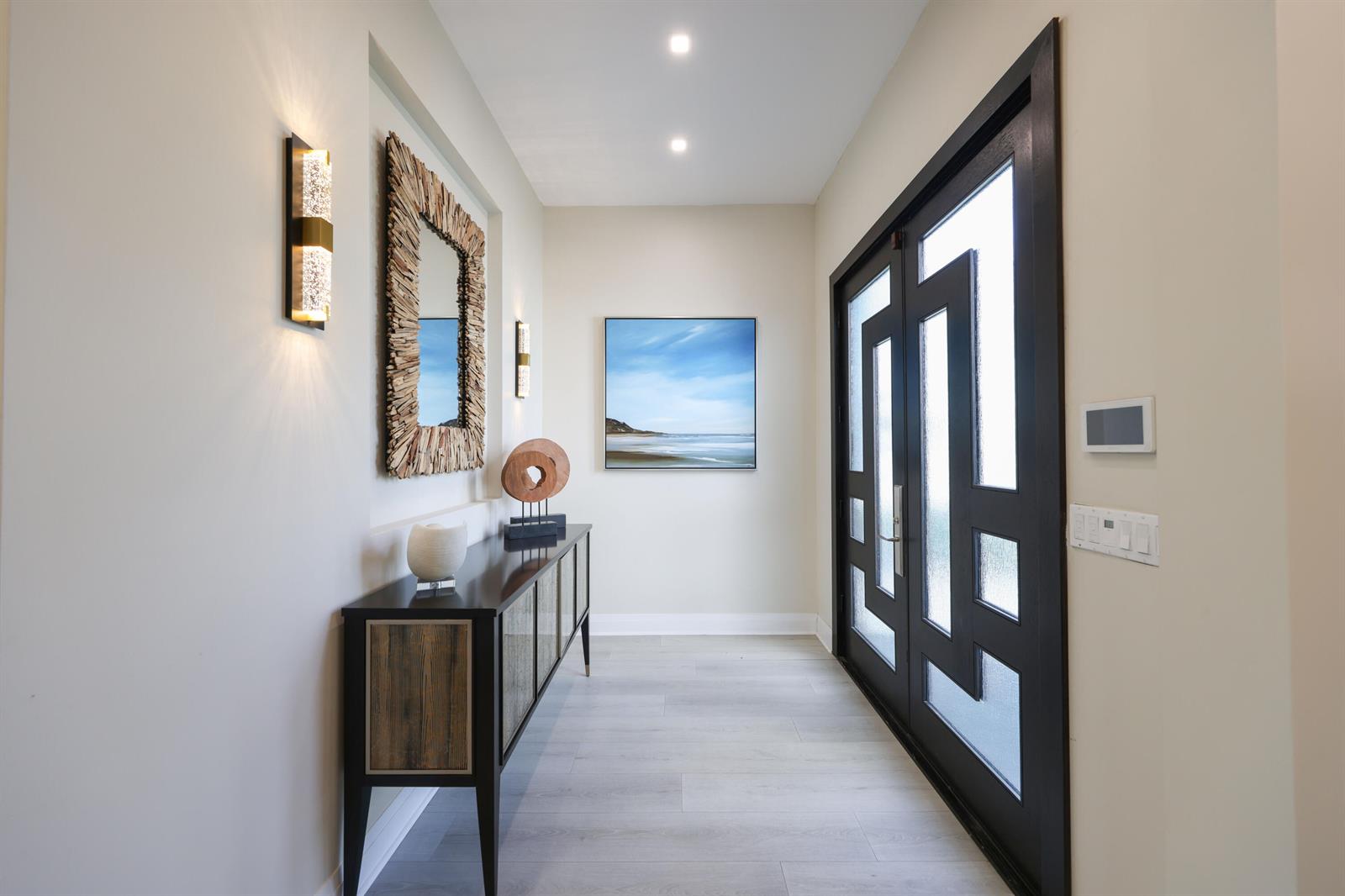 A modern entryway features a dark wood console table, a textured mirror, and double glass doors — 125 Marlin Drive, Ocean Ridge FL 33435, OCEAN RIDGE, FL