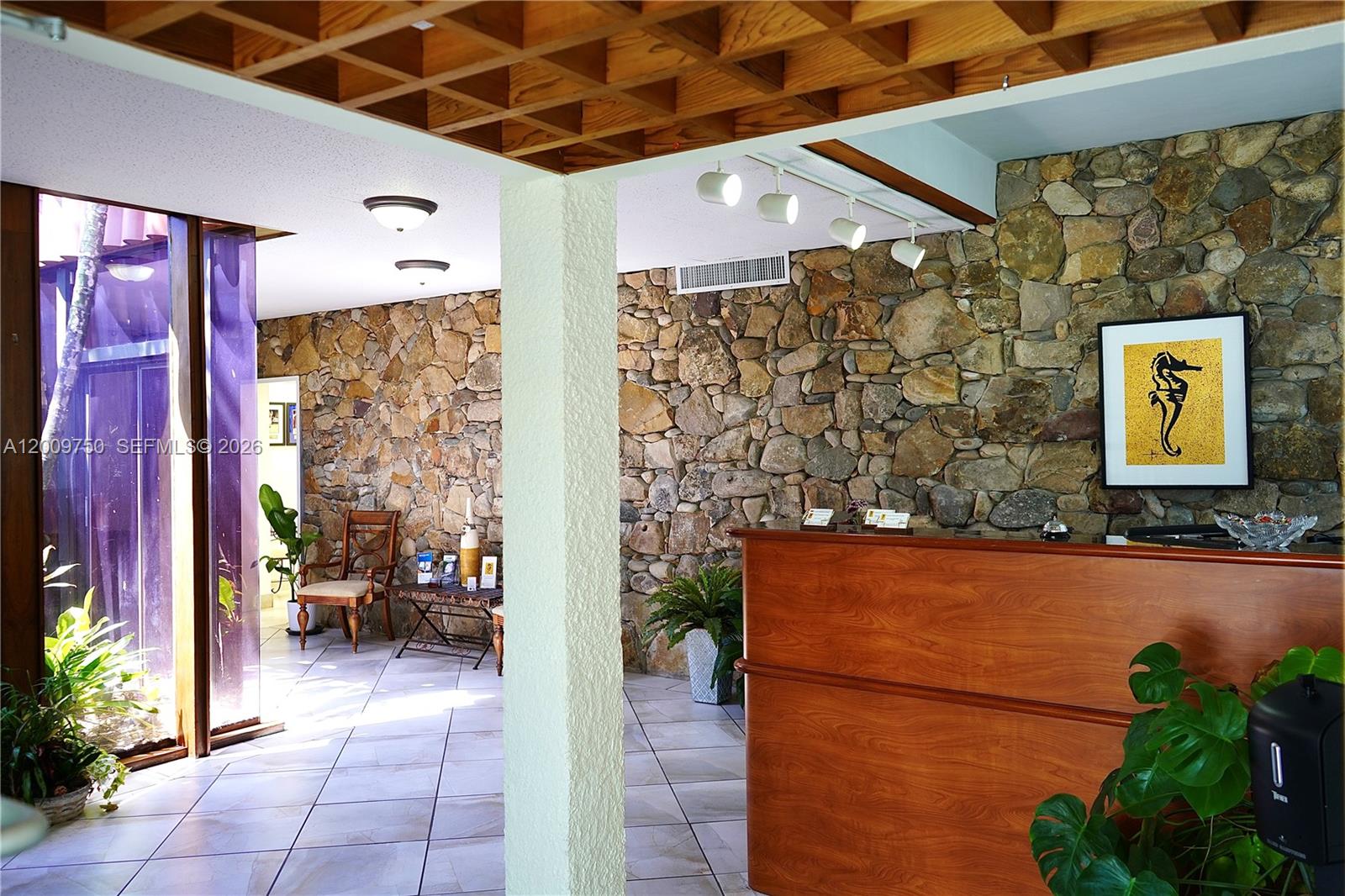 A reception area features a wood-paneled desk, stone walls, and a coffered wooden ceiling — 150 Westward Dr # 2, Miami Springs FL 33166, MIAMI SPRINGS, FL
